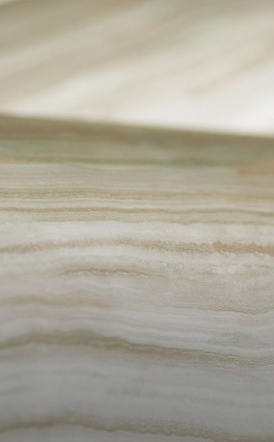 Detailaufnahme einer Kunststoffoberfläche mit natürlicher Holzoptik und feiner Maserung in Beige- und Cremetönen